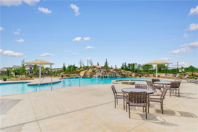 view of swimming pool with a patio, pool water feature, and a hot tub