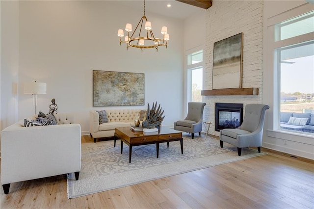 living room featuring a stone fireplace, wood-type flooring, and a wealth of natural light