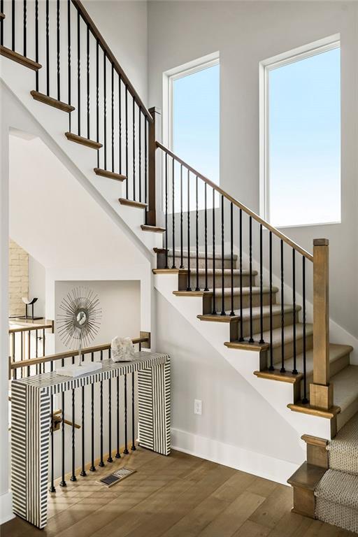 stairs featuring a healthy amount of sunlight and hardwood / wood-style flooring