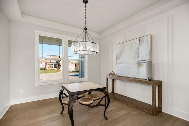 dining room with a raised ceiling, wood-type flooring, and an inviting chandelier