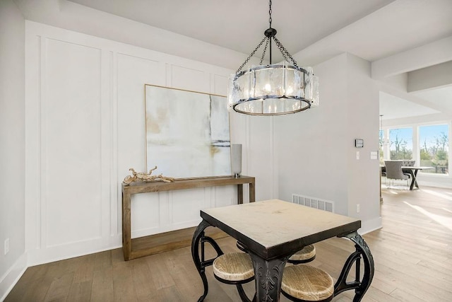 dining area with an inviting chandelier and light hardwood / wood-style flooring