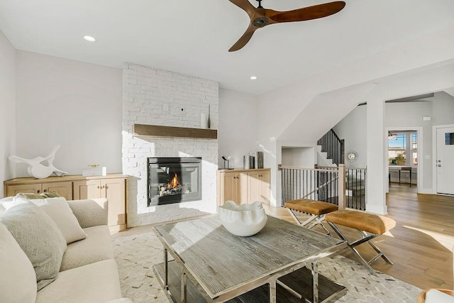 living room with ceiling fan, a fireplace, and light hardwood / wood-style floors