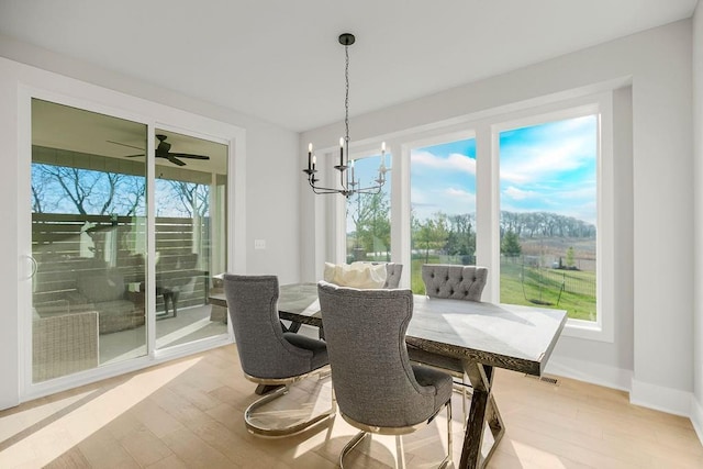 dining room with a wealth of natural light, wood-type flooring, and ceiling fan with notable chandelier