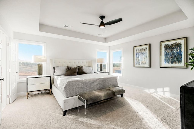 carpeted bedroom featuring multiple windows, a tray ceiling, and ceiling fan