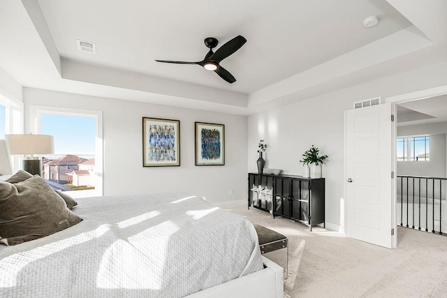 carpeted bedroom featuring a raised ceiling and ceiling fan