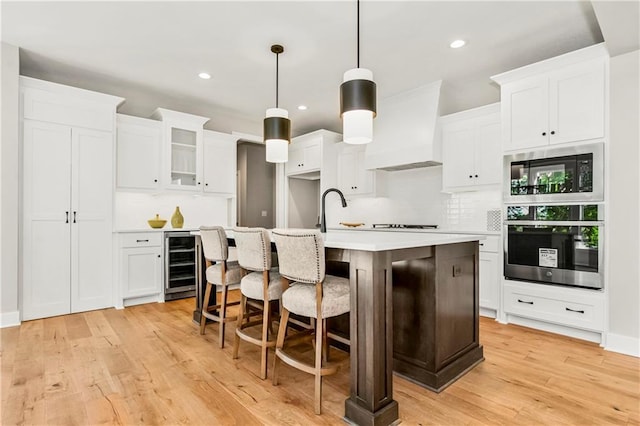 25025 W 92nd St, Lenexa, KS 66227 - kitchen with an island with sink, light wood-style flooring, oven, built in microwave, and wine cooler