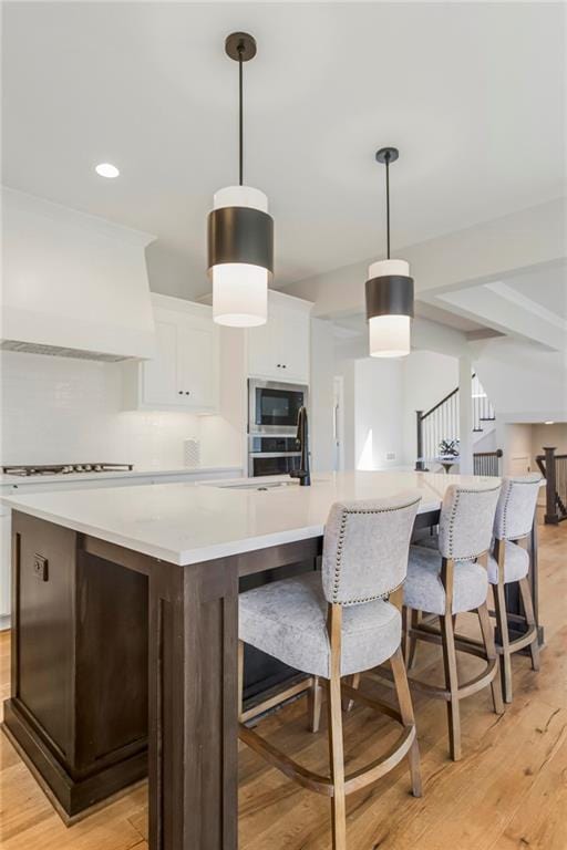25025 W 92nd St, Lenexa, KS 66227 - kitchen featuring light wood-style floors, cooktop, a spacious island, white cabinetry, and light countertops