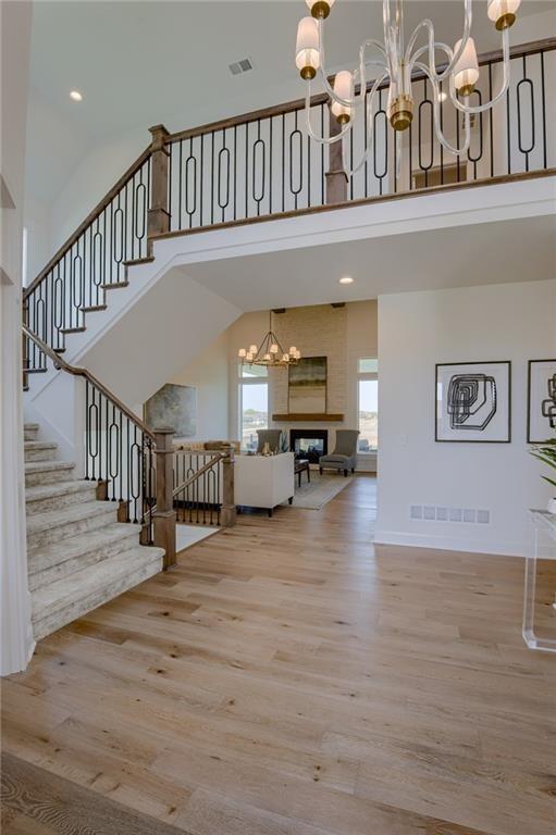 interior space featuring a notable chandelier, hardwood / wood-style flooring, high vaulted ceiling, and a large fireplace