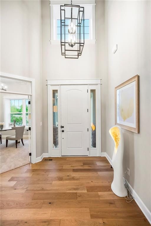 16388 S Brougham Dr, Olathe, KS 66062 - foyer entrance with baseboards, a high ceiling, light wood-style flooring, and a notable chandelier
