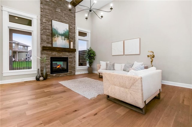 16388 S Brougham Dr, Olathe, KS 66062 - living room featuring a stone fireplace, a towering ceiling, wood finished floors, baseboards, and a chandelier