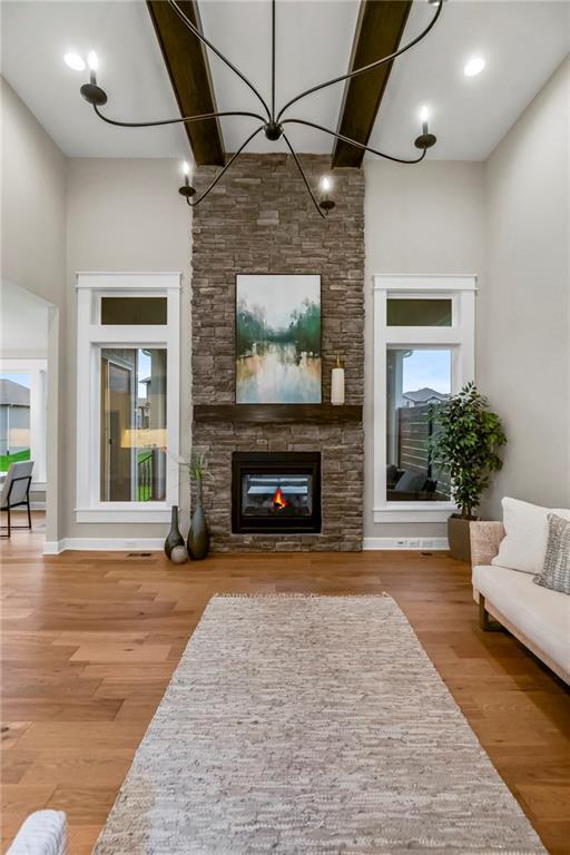 16388 S Brougham Dr, Olathe, KS 66062 - living room featuring a stone fireplace, a towering ceiling, and wood finished floors