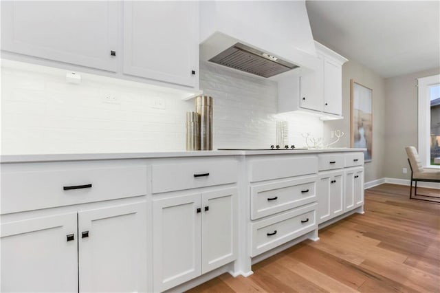 16388 S Brougham Dr, Olathe, KS 66062 - kitchen featuring backsplash, white cabinetry, light countertops, black electric stovetop, and light wood-style flooring