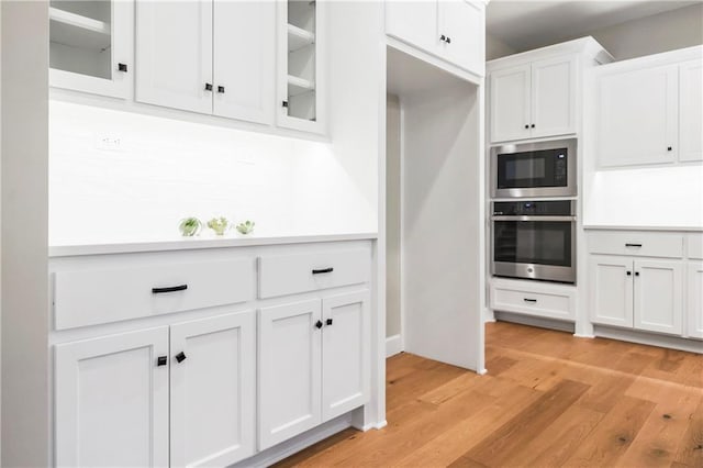 16388 S Brougham Dr, Olathe, KS 66062 - kitchen featuring glass insert cabinets, light wood-style floors, oven, white cabinetry, and built in microwave