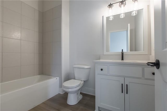 full bathroom with toilet, hardwood / wood-style floors, tiled shower / bath combo, and vanity with extensive cabinet space