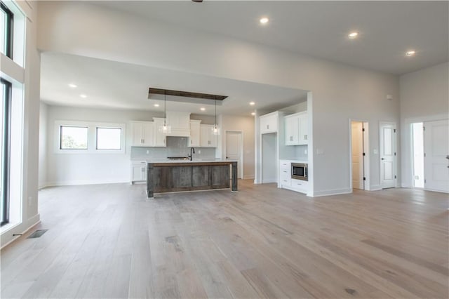 unfurnished living room featuring a high ceiling, sink, and light hardwood / wood-style flooring