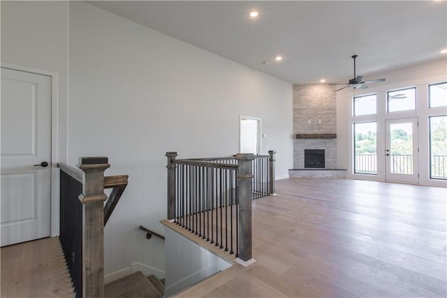 interior space with a stone fireplace, a high ceiling, light hardwood / wood-style floors, and ceiling fan