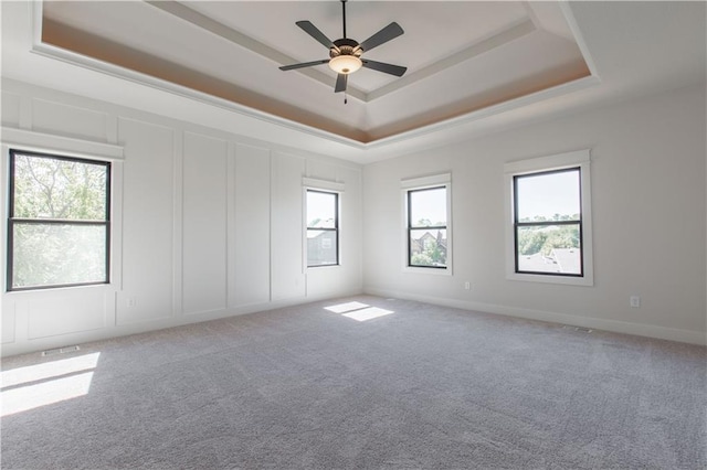 carpeted empty room featuring plenty of natural light, a tray ceiling, and ceiling fan