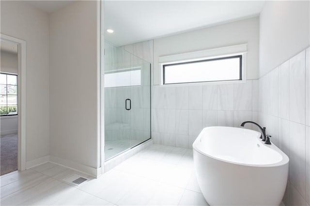 bathroom featuring tile flooring, shower with separate bathtub, and tile walls