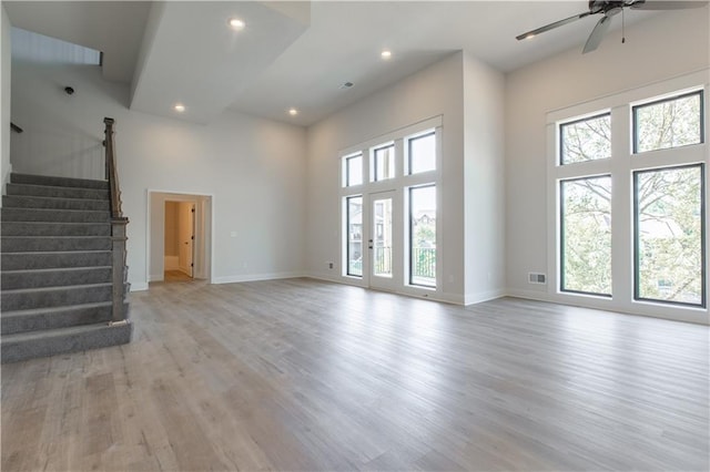 unfurnished living room featuring plenty of natural light, ceiling fan, and light wood-type flooring