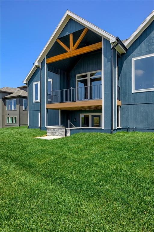 rear view of house with a balcony and a yard