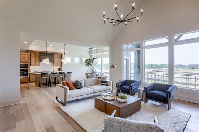 living room featuring a high ceiling, a notable chandelier, and light hardwood / wood-style floors