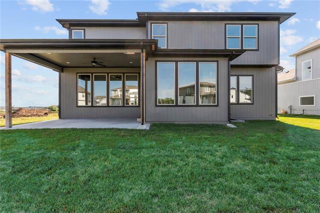 back of property with ceiling fan, a yard, and a patio