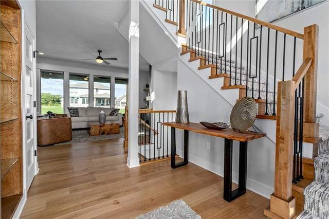 stairs with ceiling fan and light hardwood / wood-style flooring