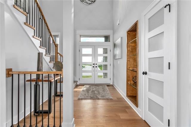 foyer featuring light wood-type flooring, a high ceiling, and french doors