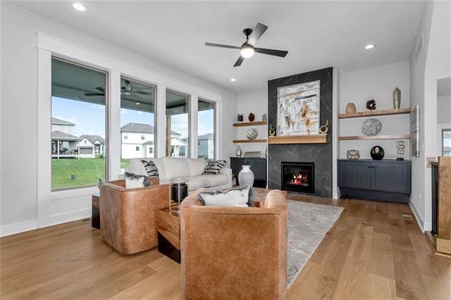 living room featuring light hardwood / wood-style floors, ceiling fan, and a fireplace