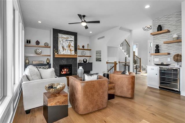 living room featuring ceiling fan, wine cooler, a large fireplace, and light hardwood / wood-style flooring