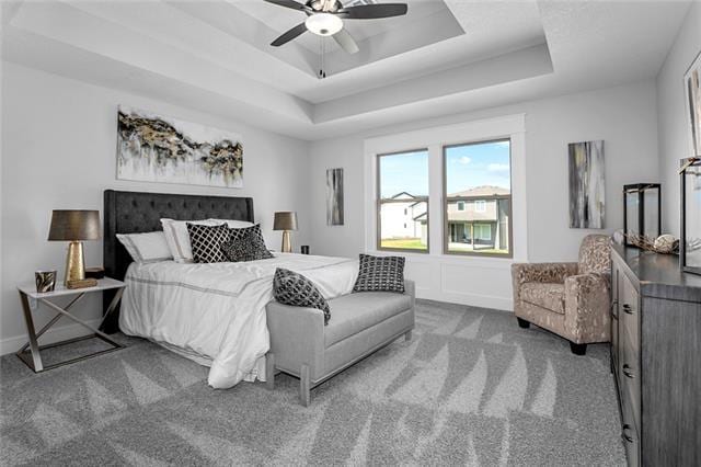 bedroom with ceiling fan, a raised ceiling, and carpet