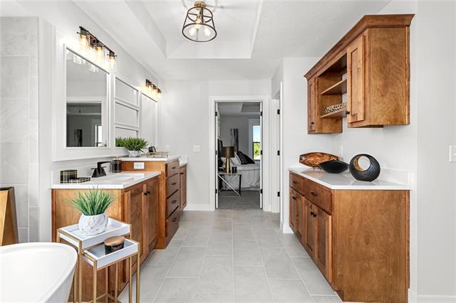 bathroom featuring double sink vanity, tile flooring, a bathing tub, and a raised ceiling