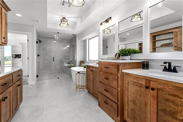 bathroom featuring independent shower and bath, a tray ceiling, tile flooring, and vanity