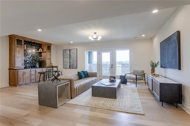 living room featuring a chandelier, light wood-type flooring, and french doors