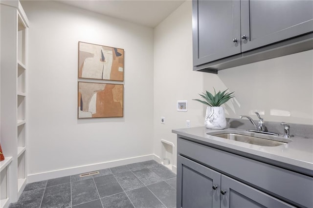 washroom with washer hookup, electric dryer hookup, cabinets, dark tile flooring, and sink