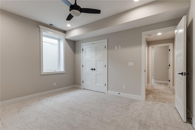 unfurnished bedroom featuring ceiling fan, light colored carpet, and a closet