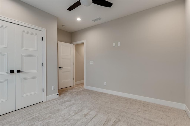 unfurnished bedroom with ceiling fan, light carpet, and a closet