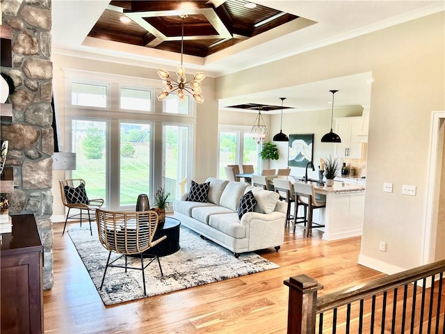 living room featuring light hardwood / wood-style floors, an inviting chandelier, coffered ceiling, and a healthy amount of sunlight