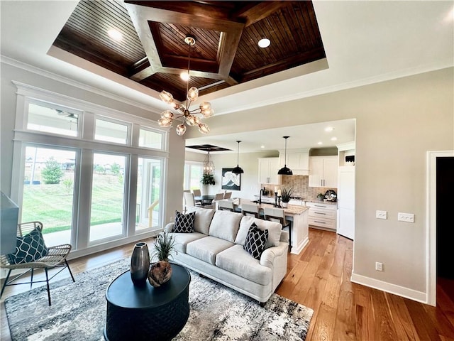 living room featuring coffered ceiling, a notable chandelier, wooden ceiling, light hardwood / wood-style flooring, and crown molding