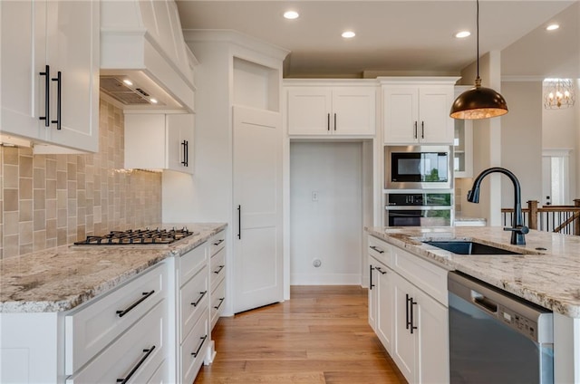 kitchen with stainless steel appliances, decorative light fixtures, custom exhaust hood, light hardwood / wood-style flooring, and backsplash