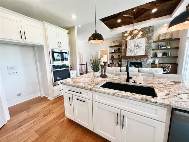 kitchen featuring coffered ceiling, appliances with stainless steel finishes, light hardwood / wood-style floors, white cabinets, and hanging light fixtures