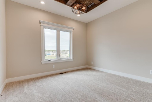 carpeted spare room with a notable chandelier