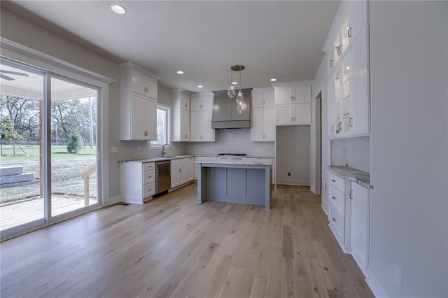 kitchen featuring dishwasher, hanging light fixtures, light hardwood / wood-style flooring, decorative backsplash, and white cabinetry