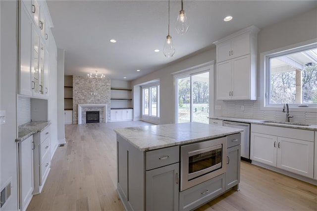 kitchen featuring backsplash, stainless steel appliances, sink, a center island, and white cabinetry