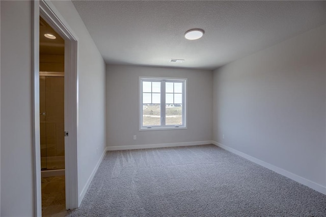 empty room with light carpet and a textured ceiling