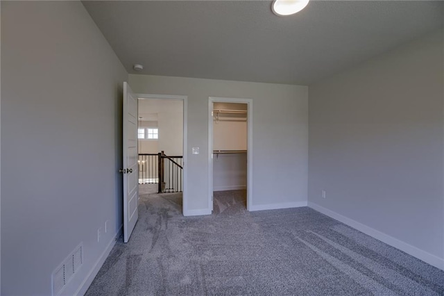 unfurnished bedroom featuring carpet, a walk in closet, and a closet