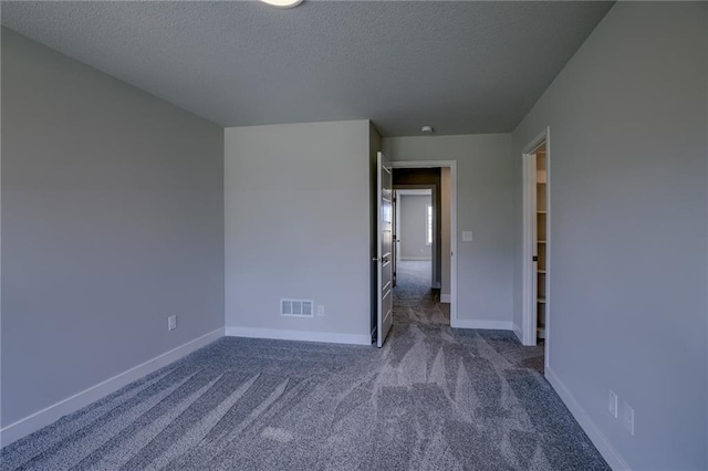 spare room with dark colored carpet and a textured ceiling