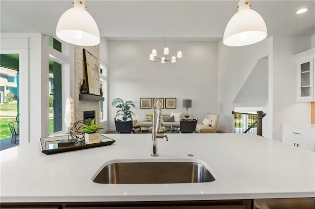 25212 W 92nd St, Lenexa, KS 66227 - kitchen with a large fireplace, a sink, light countertops, pendant lighting, and open floor plan