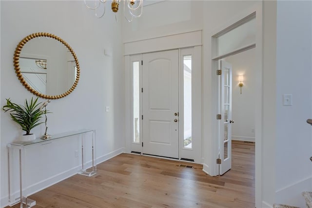 entryway with an inviting chandelier and light hardwood / wood-style flooring