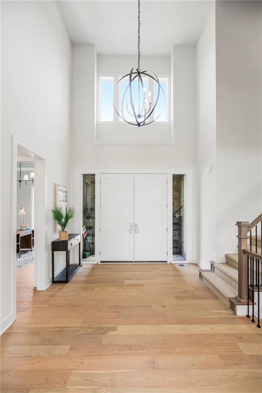 entryway featuring a towering ceiling, a chandelier, and light hardwood / wood-style floors